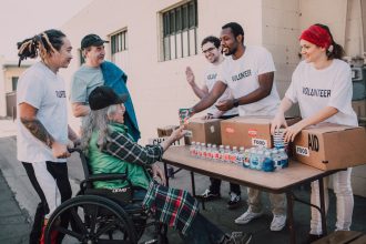 Voluntários distribuem água engarrafada e mantimentos a pessoas em uma ação comunitária de apoio.