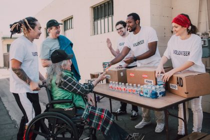 Voluntários distribuem água engarrafada e mantimentos a pessoas em uma ação comunitária de apoio.