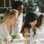 Três jovens cientistas trabalham juntas em um laboratório iluminado.